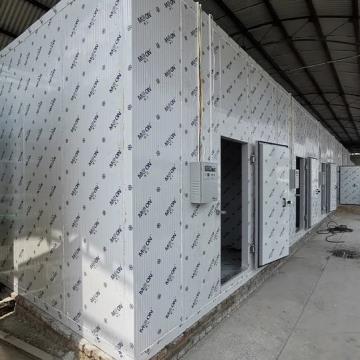 Long insulated cold room enclosure with access doors inside a facility